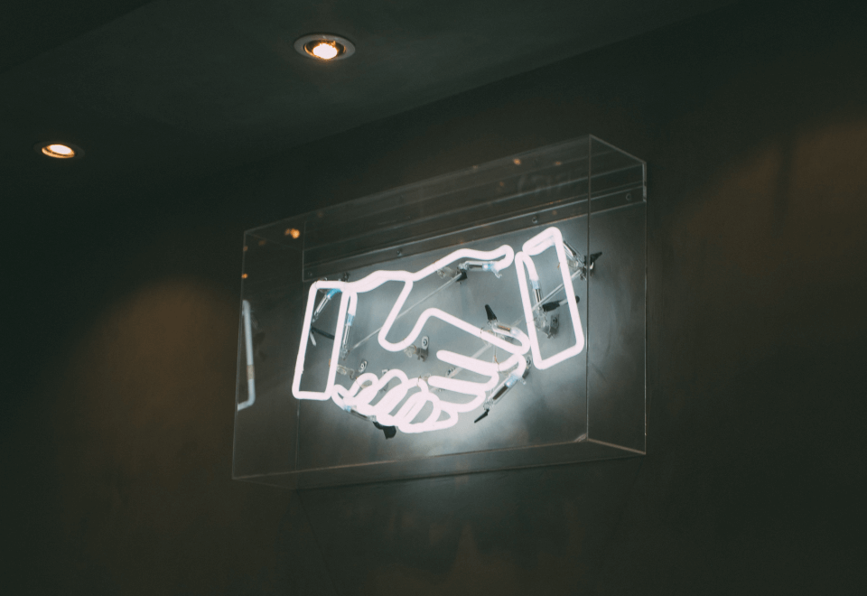 A lit up sign of a handshake